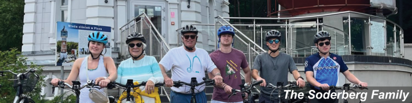 six people on bikes outside a big tower smiling at the camera