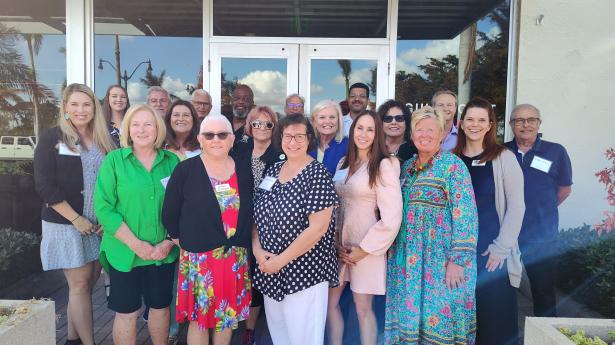 23 people stand together smiling outside of Gulf Coast Community Foundation's Venice Headquarters.