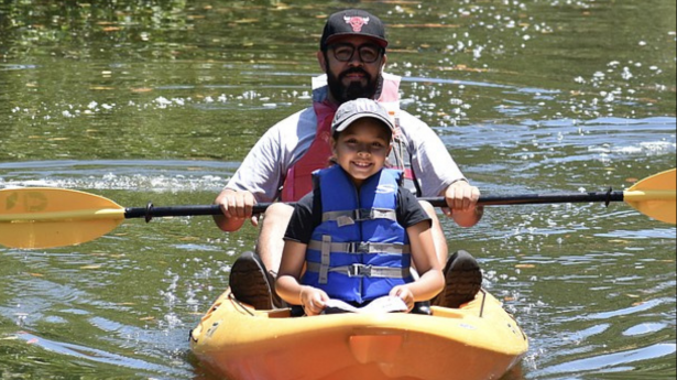  A man and boy in a yellow kayak on the water.