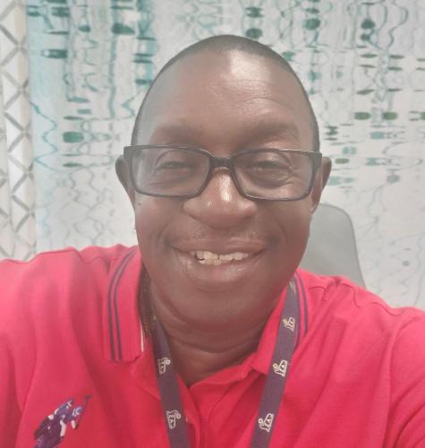 One African American man with black glasses and red polo shirt smiles at camera.