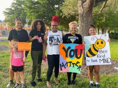 Six women, including small girl, stand holding "You Matter" type of uplifting signs.