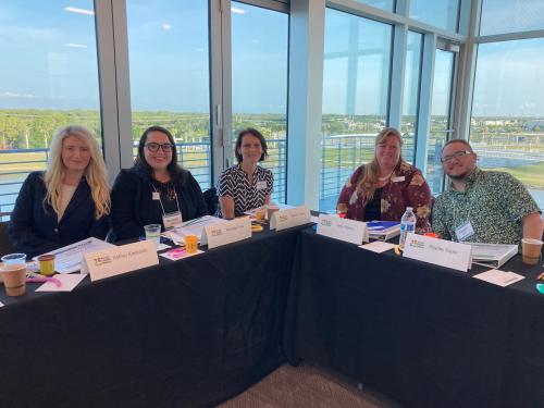 Four people sitting inside at table, smiling at camera from the 2022 Gulf Coast Leadership Institute class.