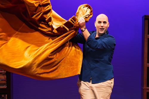 Man stands on stage with orange cloth